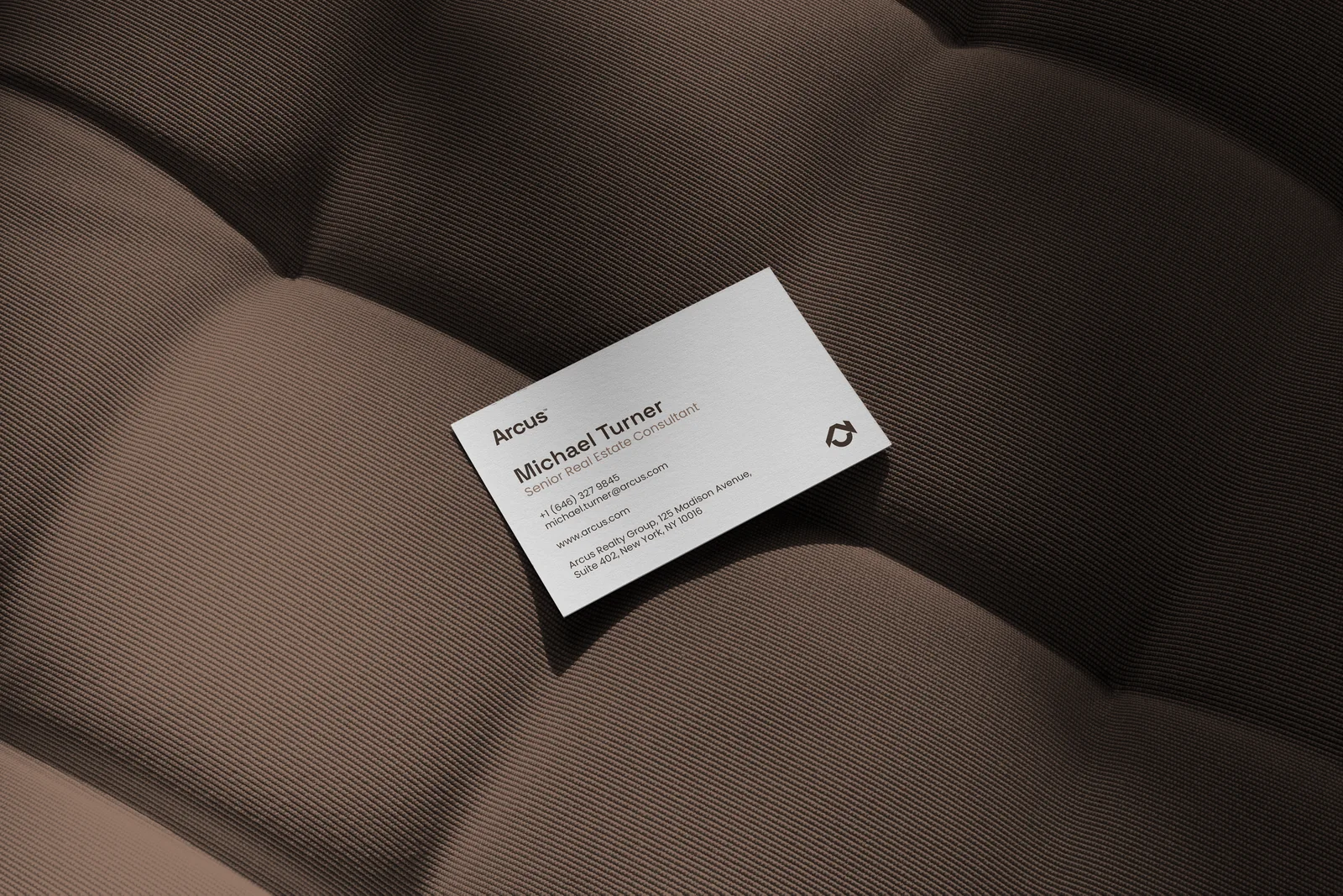 Arcus business card photographed on a dark textured surface